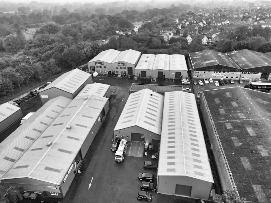 Exterior view of a modern commercial building at Harold Park Industrial Estate with dark grey panelled walls and narrow vertical glass windows. Several cardboard boxes and packing materials are placed